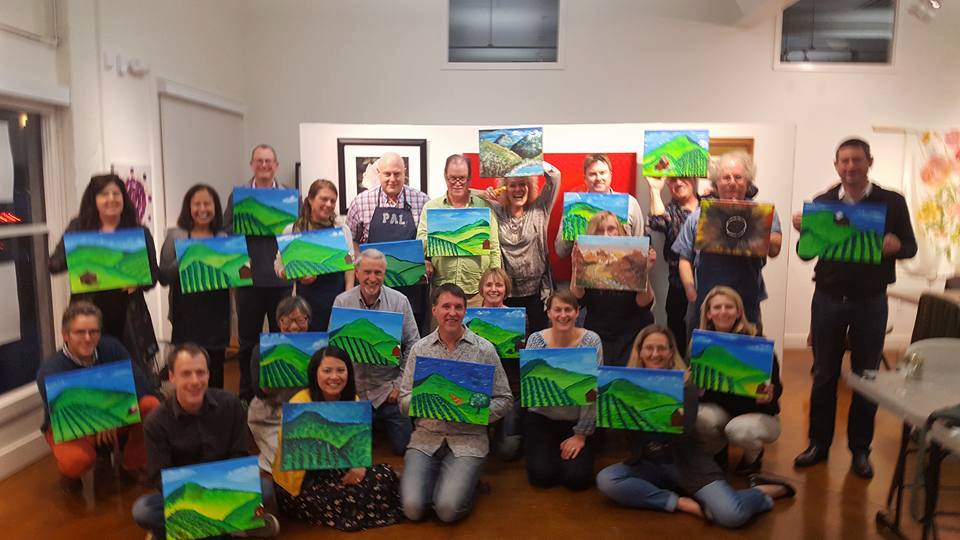 Group smiling and holding their finished paintings
