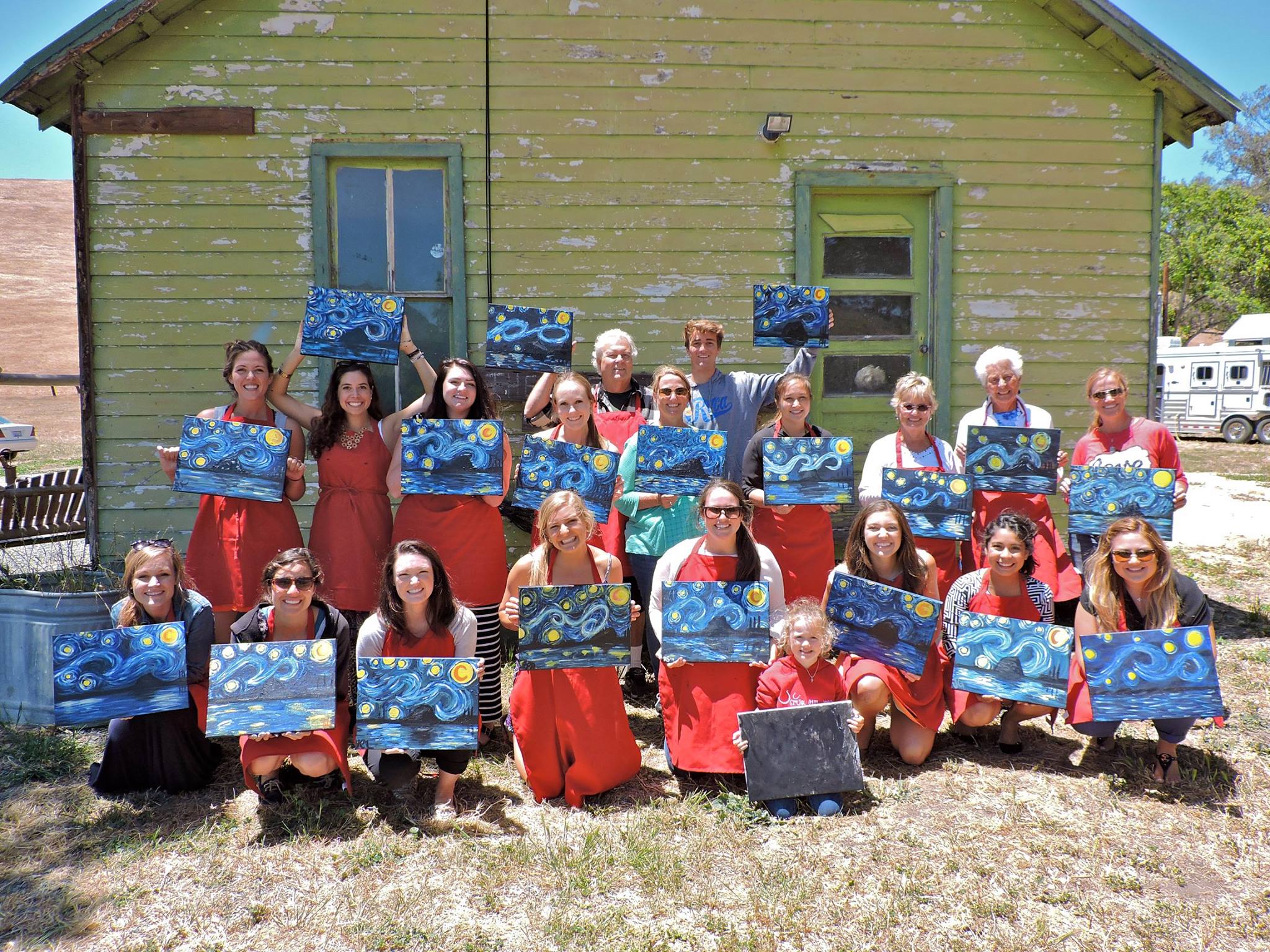 Group smiling and holding their finished paintings