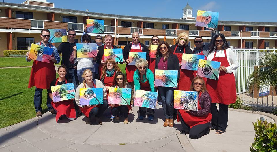 Group smiling and holding their finished paintings