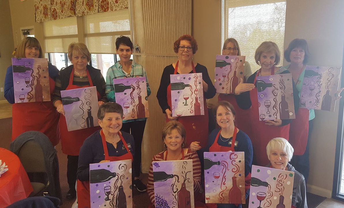 Party guests smiling and holding up their finished paintings