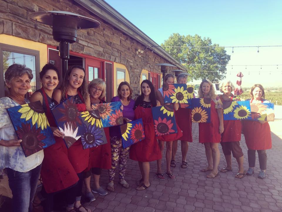Group smiling and holding their finished paintings