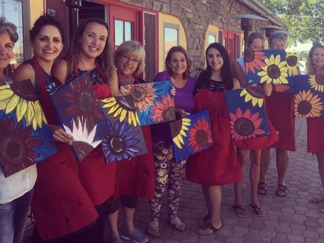 Guests smiling and holding their finished paintings